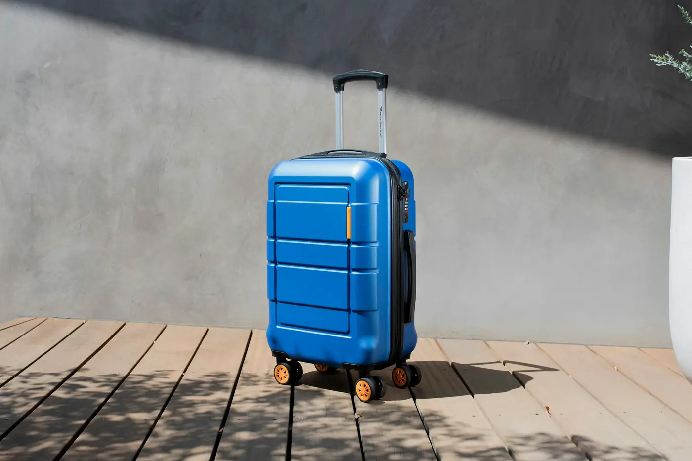 Blue hard-shell suitcase standing on a wooden deck