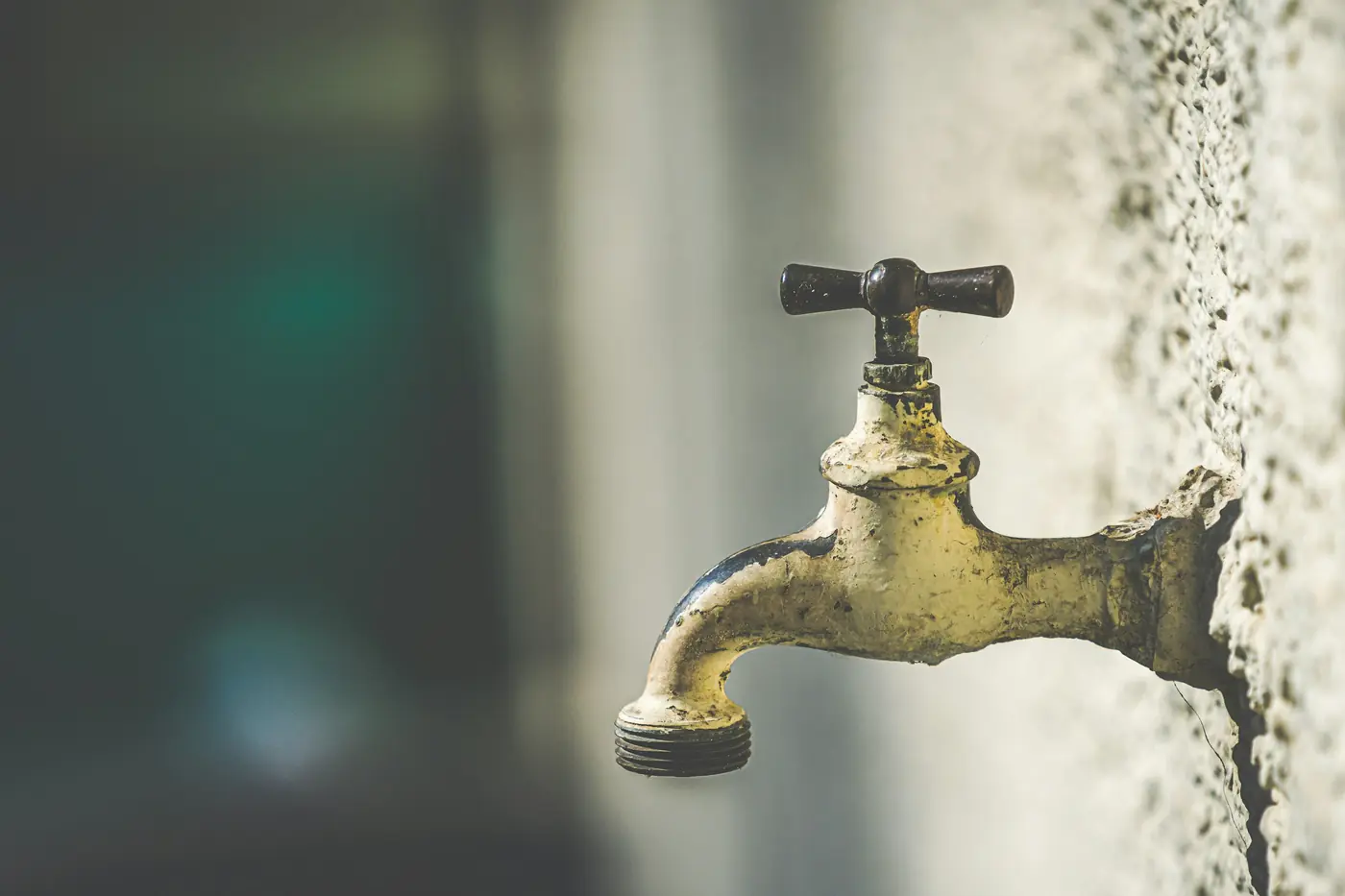Weathered brass tap on a textured, mineral-stained wall