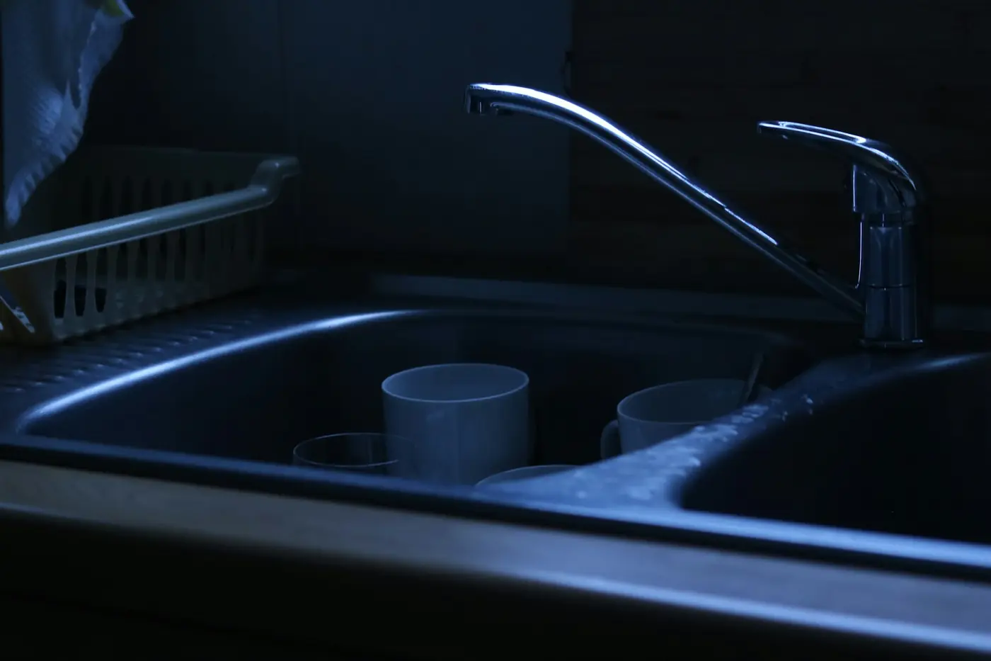 Dishes and cups left in a dark kitchen sink