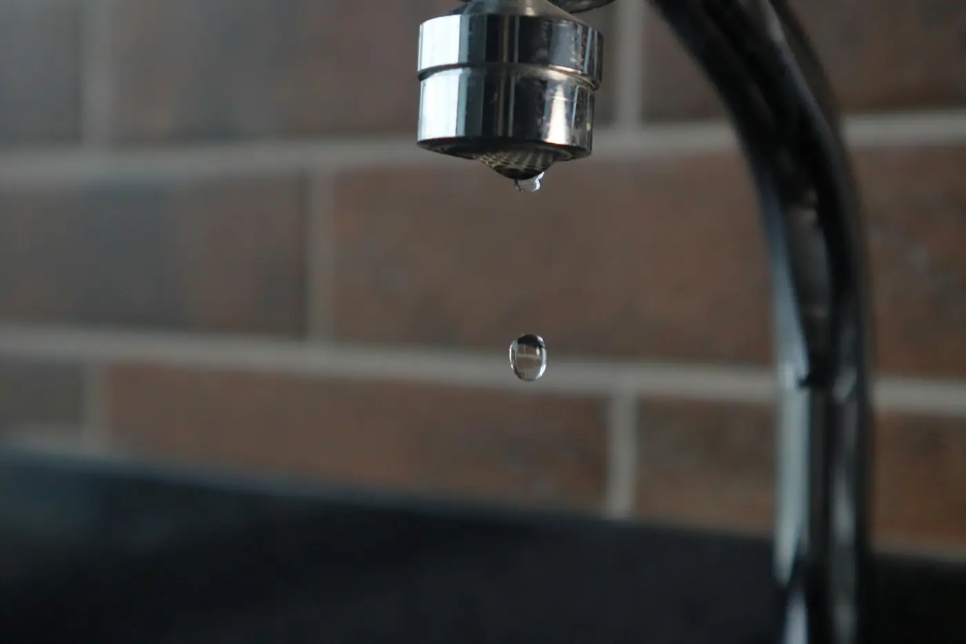 Kitchen faucet with a single water drop hanging from the spout