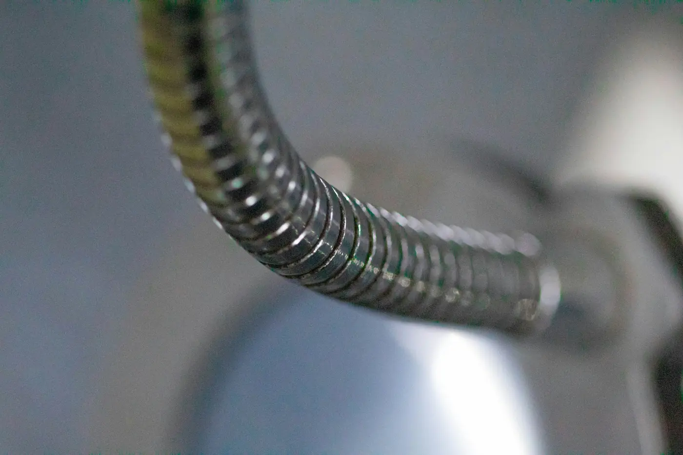 Close-up of a flexible coiled metal hose bending in a curve
