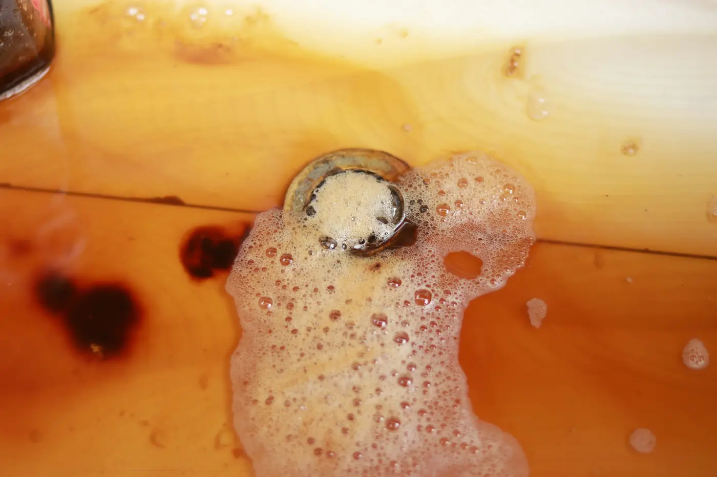 Murky brown water and foam pooling around a clogged drain