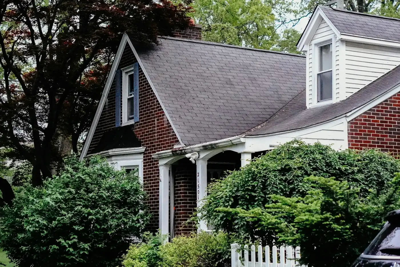 Brick and white siding house with a dormer and front shrubs