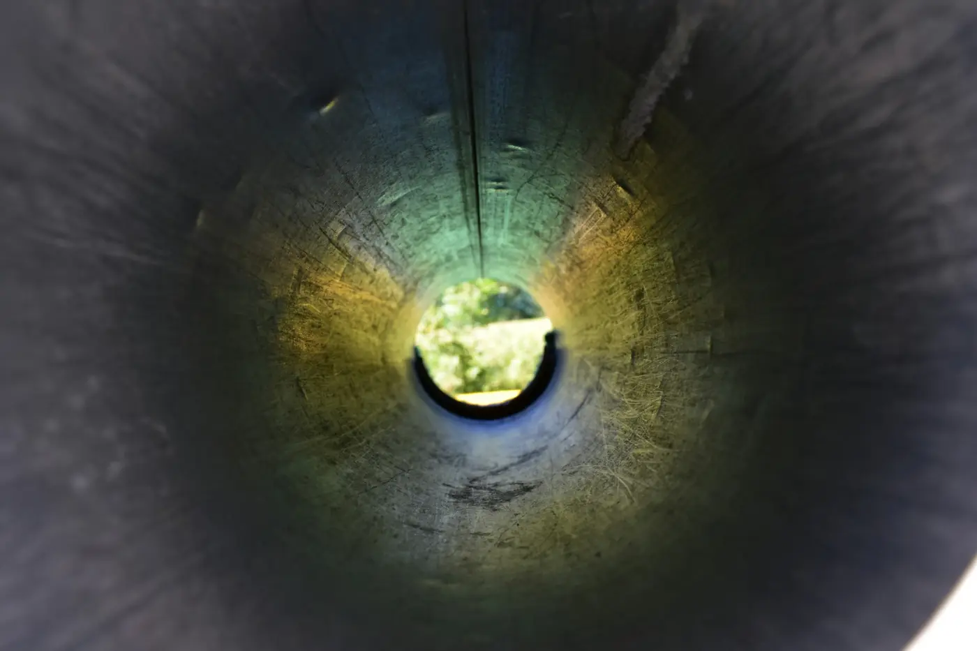View down the inside of a pipe toward a lit opening