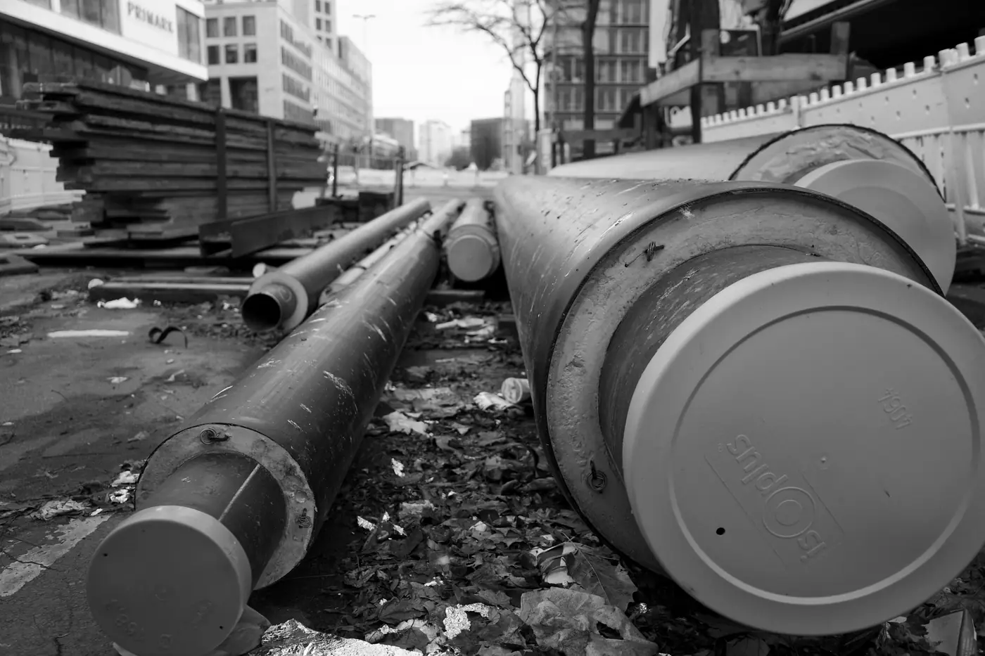Black and white photo of large pipes lying at a construction site