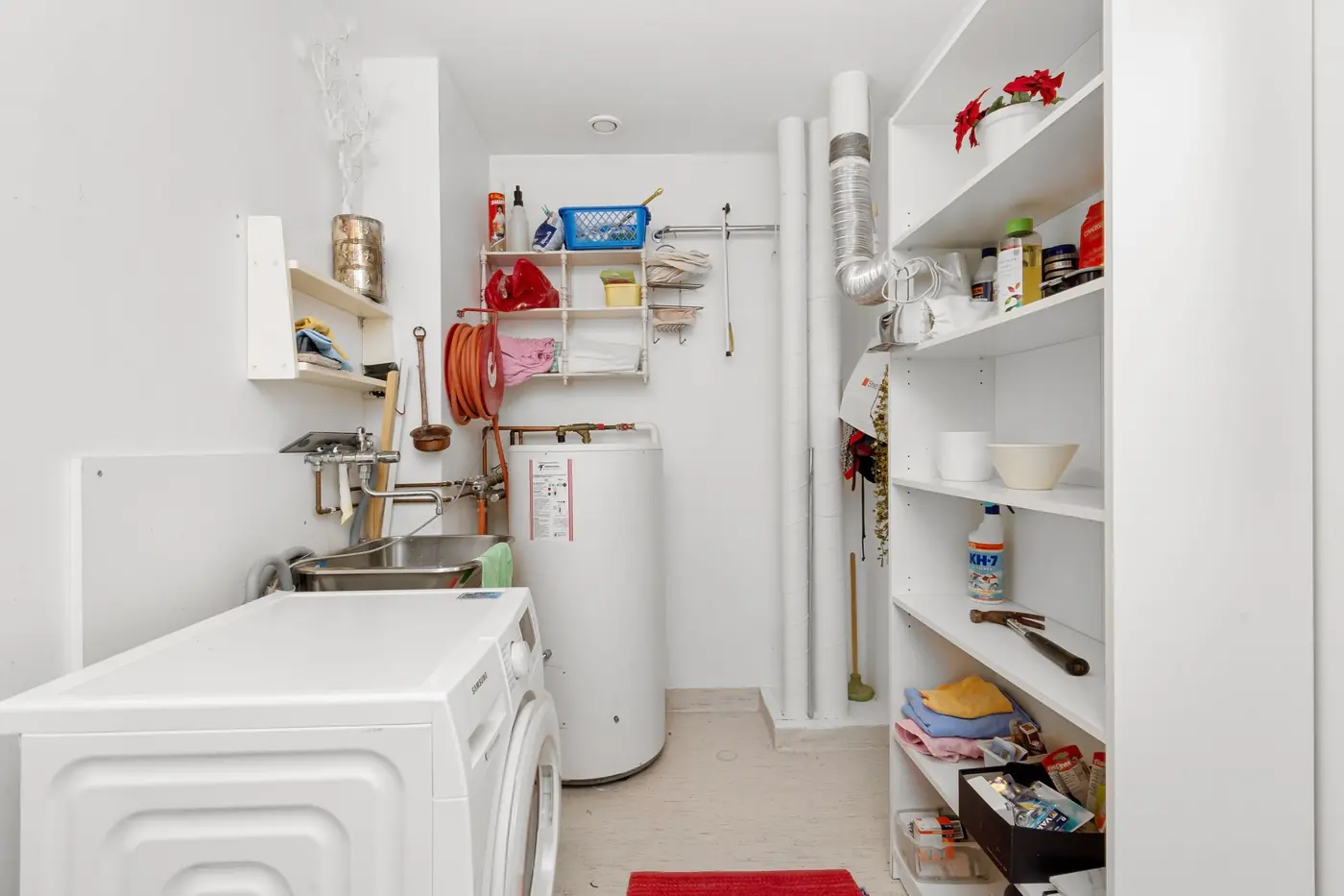 Home laundry room with a washing machine and a tank water heater