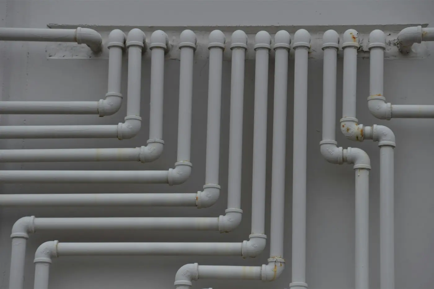 Neat runs of new white water pipes along a wall
