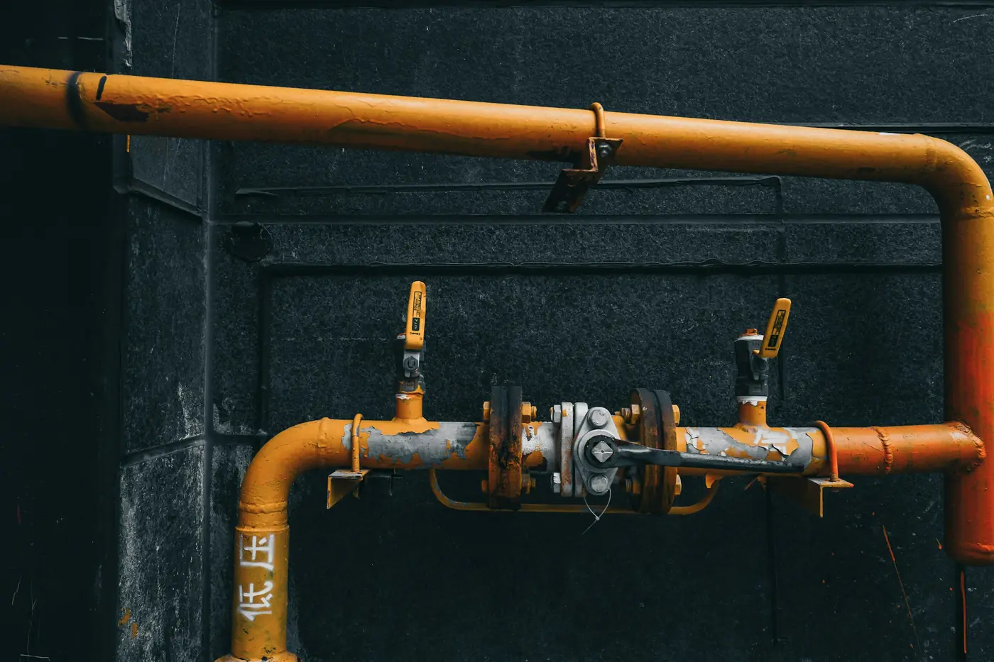 Orange utility pipes with fittings and valves on a dark wall