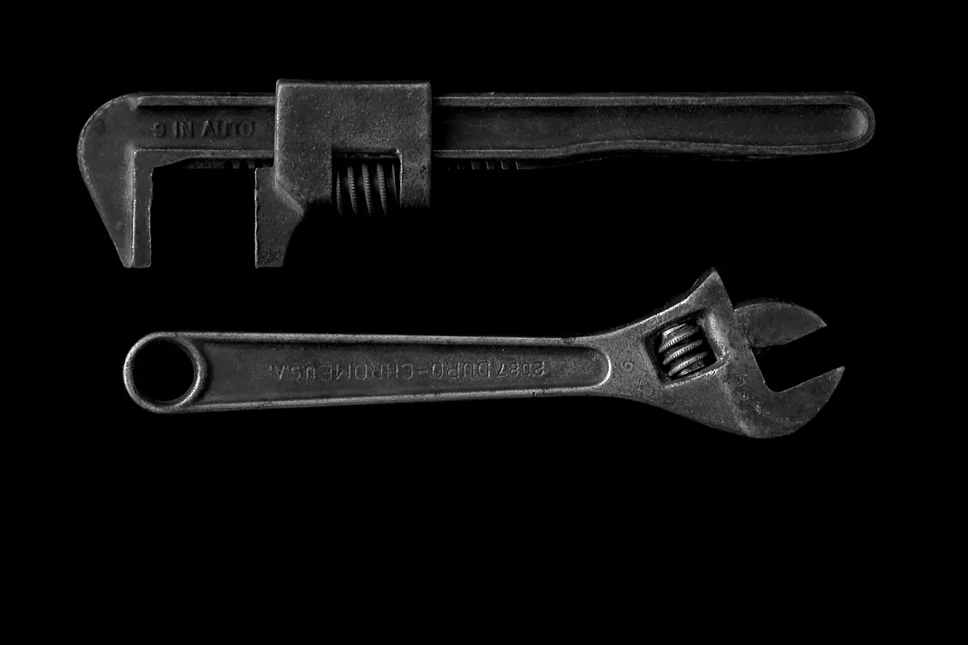 Pipe wrench and adjustable wrench on a black background