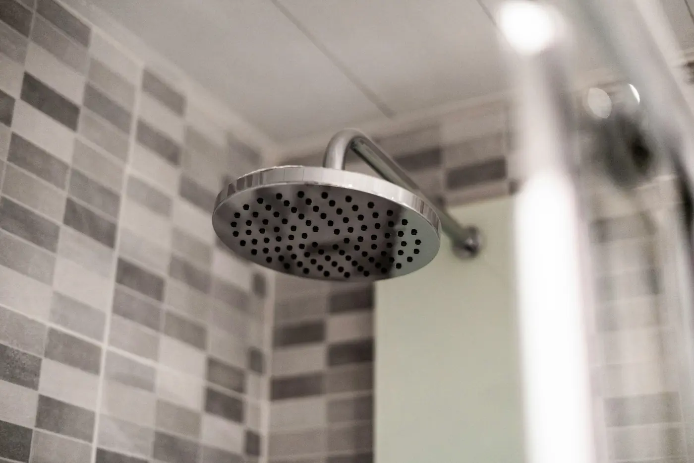 Stainless steel rain shower head in a tiled bathroom