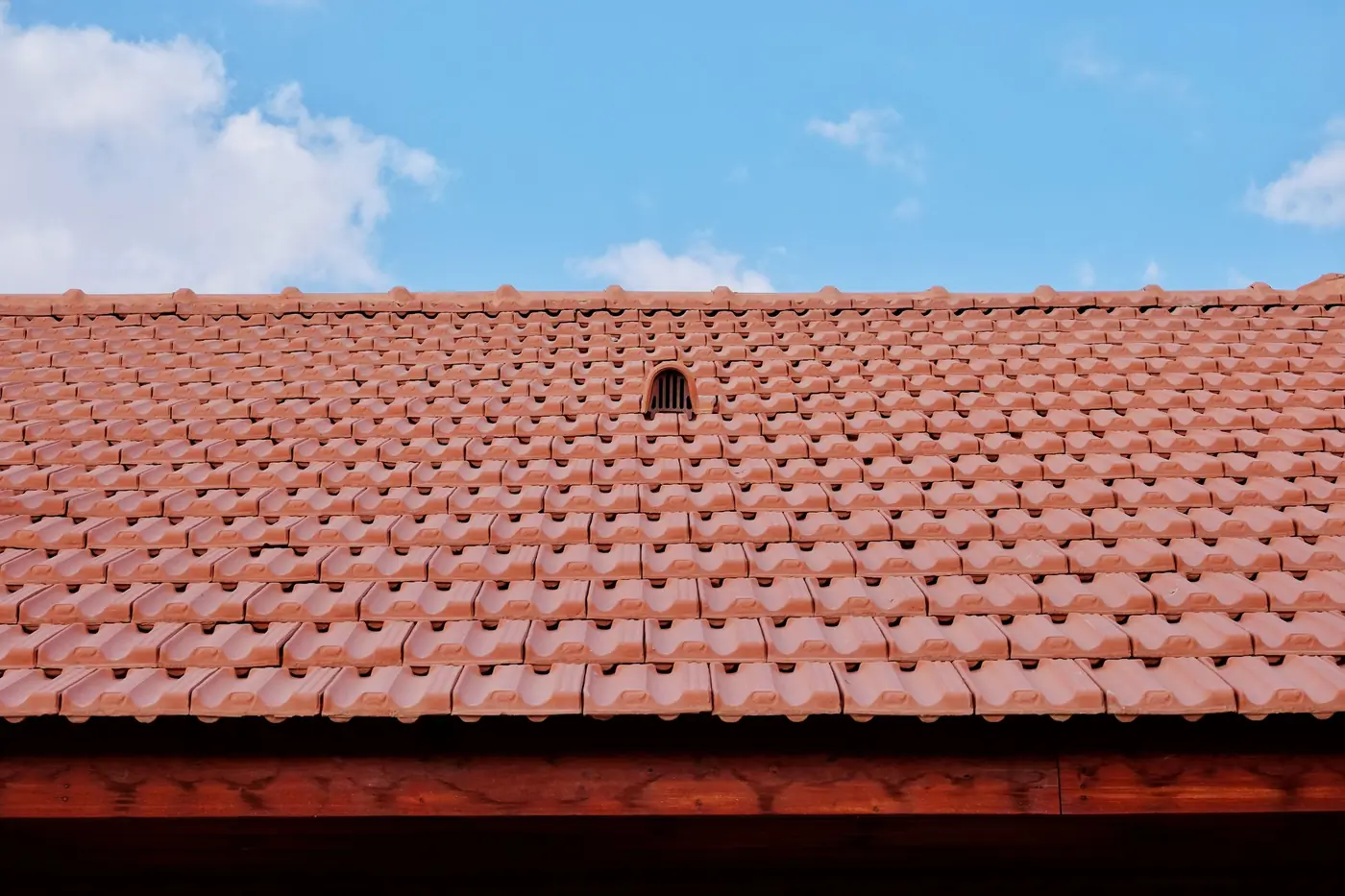 Vent cap on a red clay tile roof under a blue sky