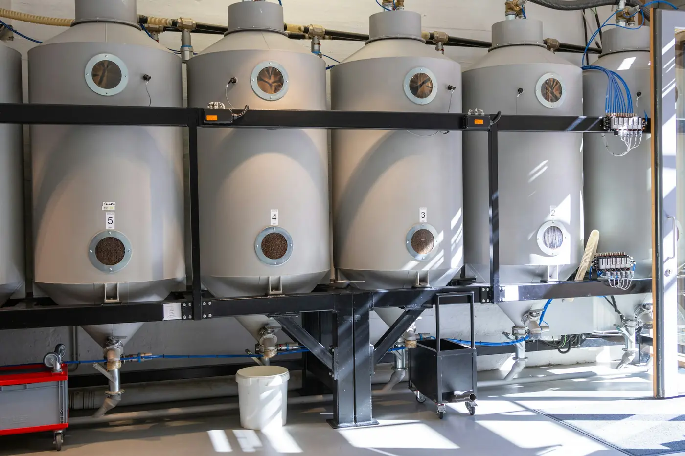 Row of stainless steel hot water tanks lined up in a utility room
