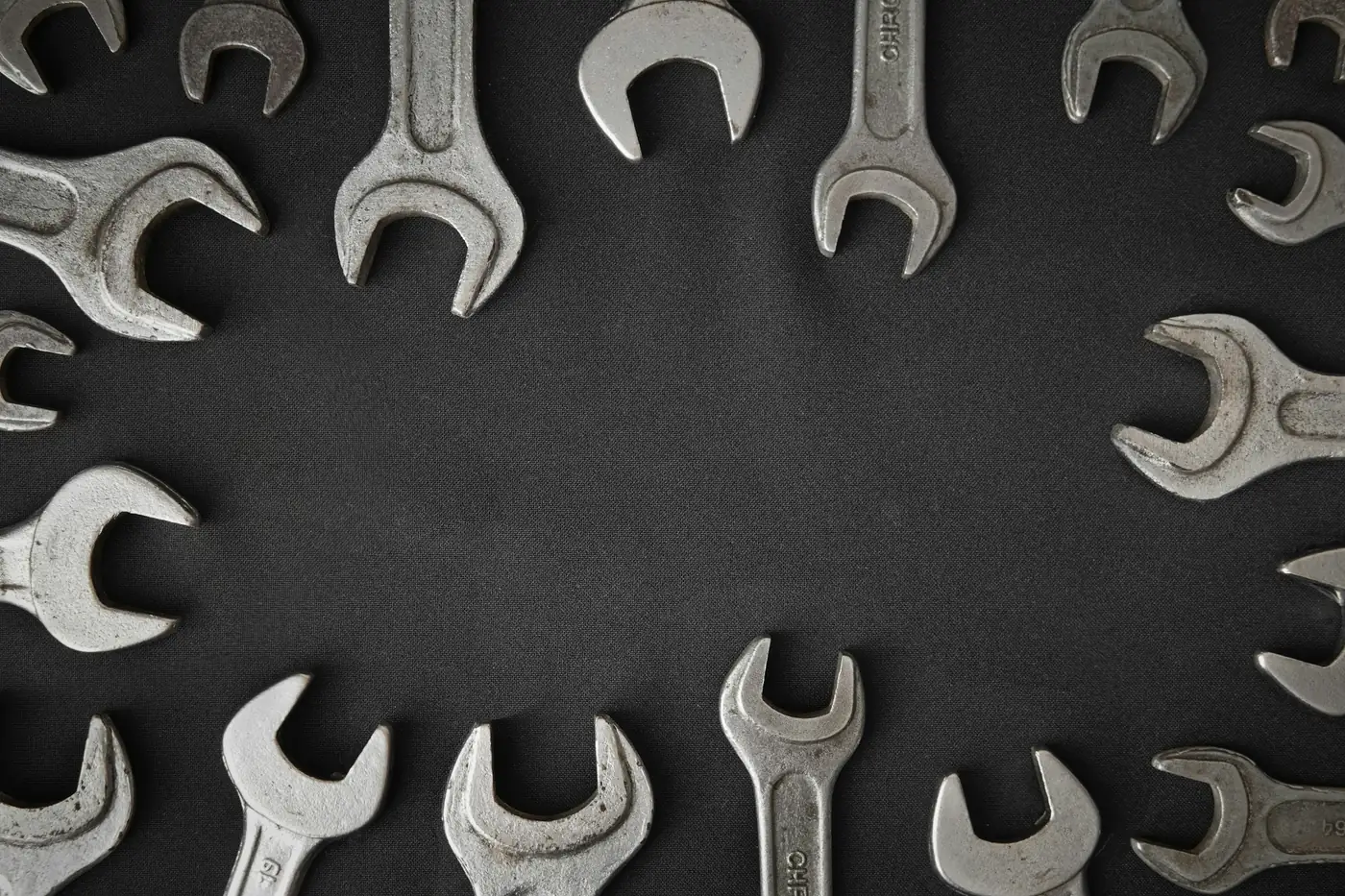 Set of steel wrenches arranged in a circle on a dark surface